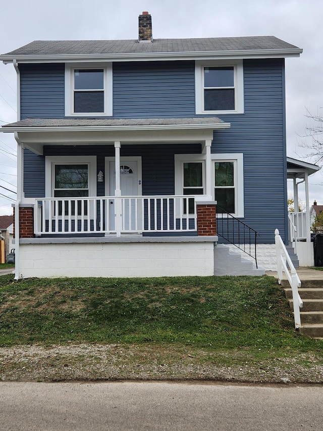 view of front of property with a front yard, a porch, and a chimney