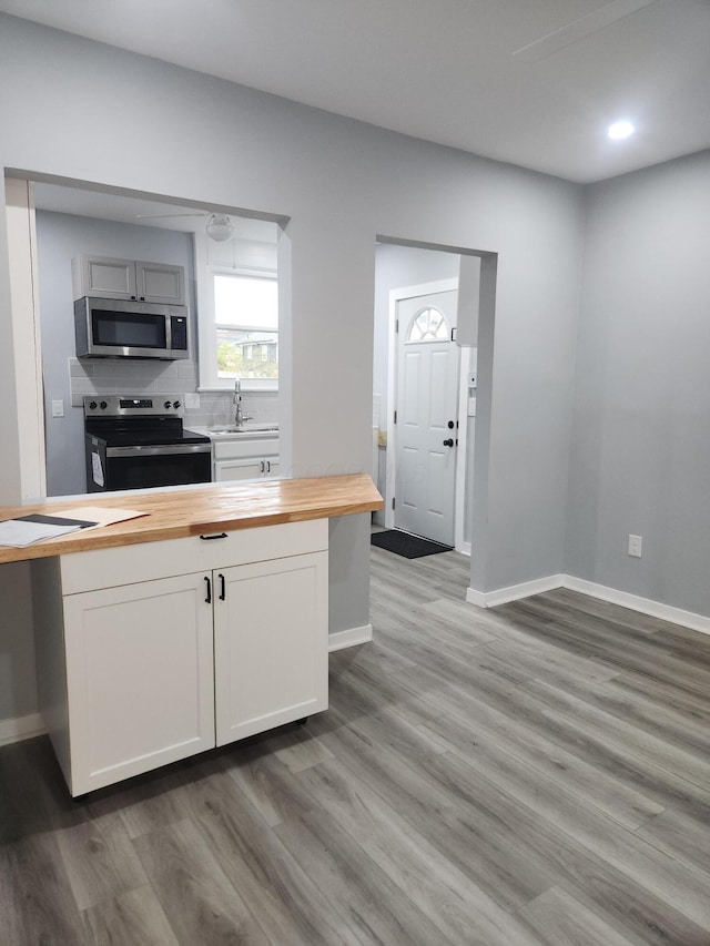 kitchen with backsplash, appliances with stainless steel finishes, butcher block counters, and light wood finished floors