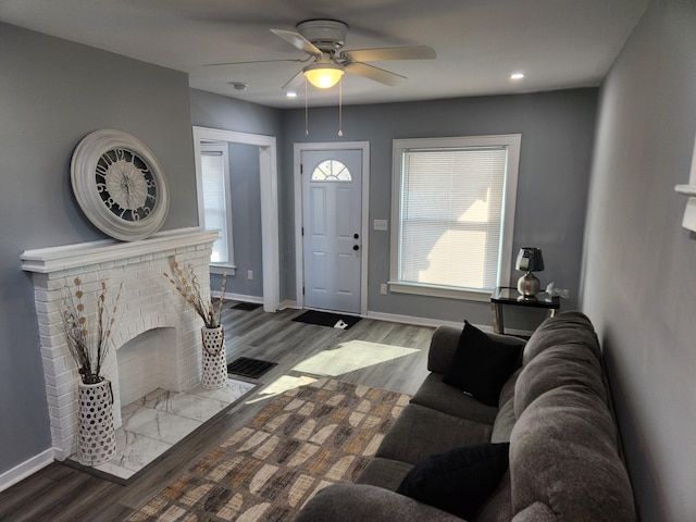 foyer entrance with a ceiling fan, wood finished floors, baseboards, recessed lighting, and a fireplace