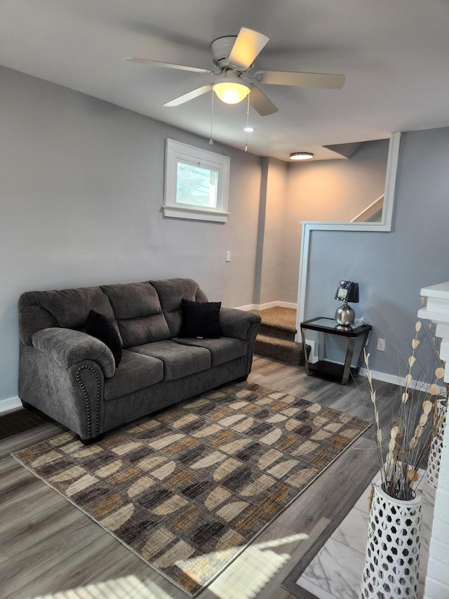 living area featuring a ceiling fan, baseboards, and wood finished floors