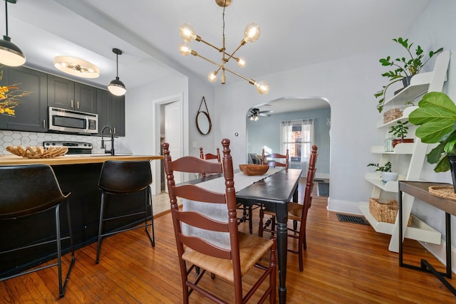 dining room with sink, ceiling fan with notable chandelier, and dark hardwood / wood-style floors