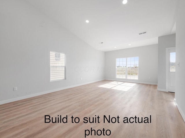 empty room with light hardwood / wood-style flooring and high vaulted ceiling