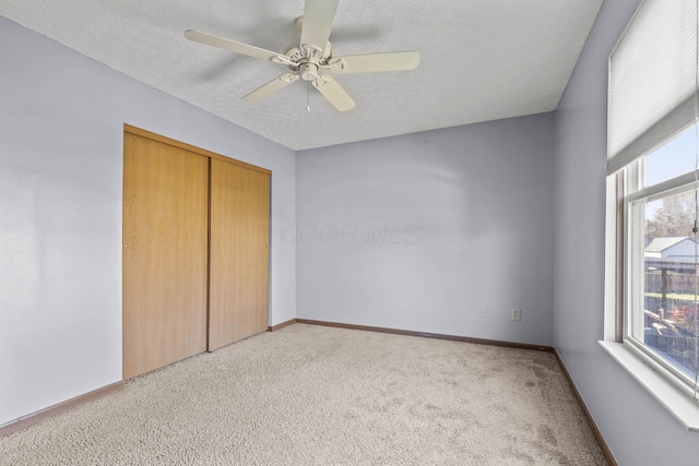 unfurnished bedroom featuring ceiling fan, a closet, a textured ceiling, and multiple windows