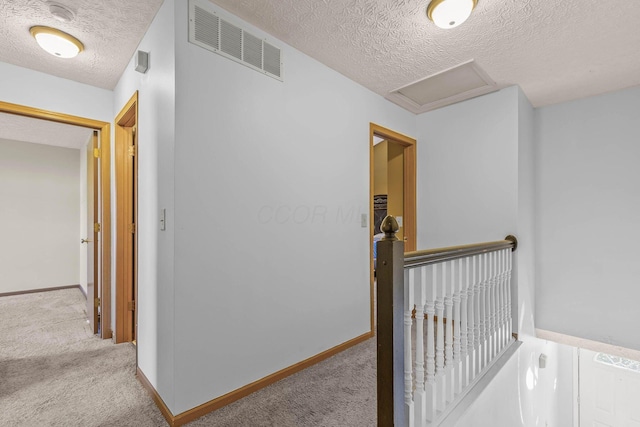 hall with a textured ceiling and light colored carpet