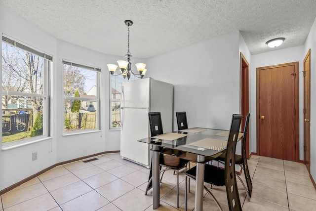 dining space with light tile patterned flooring, a textured ceiling, and an inviting chandelier