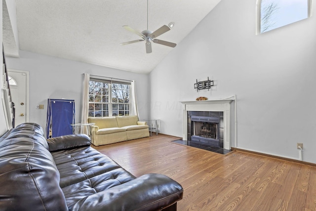 living room with a fireplace, a textured ceiling, hardwood / wood-style flooring, and high vaulted ceiling