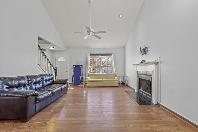 living room featuring ceiling fan, wood-type flooring, a fireplace, and high vaulted ceiling