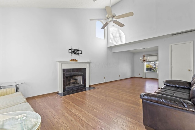 living room with a fireplace, wood-type flooring, ceiling fan with notable chandelier, and high vaulted ceiling