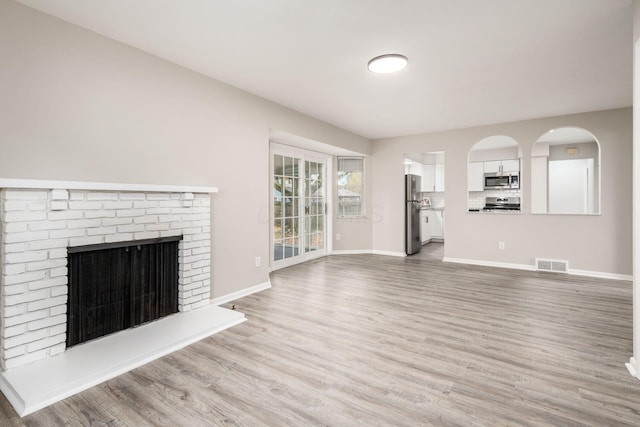 unfurnished living room with hardwood / wood-style flooring and a brick fireplace