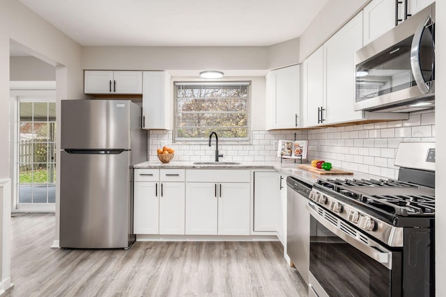 kitchen with white cabinets, stainless steel appliances, plenty of natural light, and sink