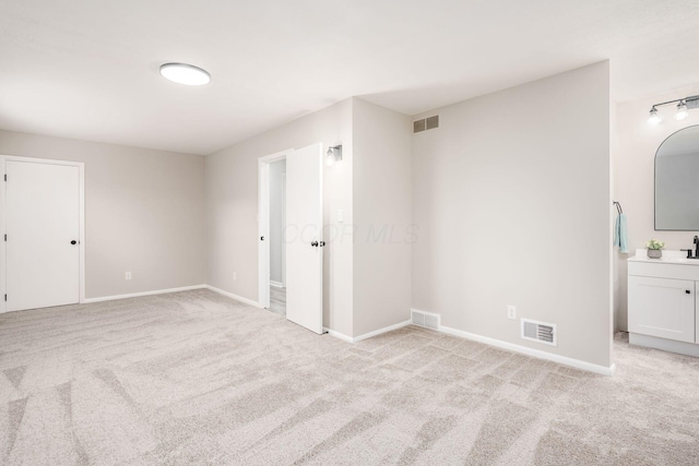 empty room featuring sink and light colored carpet