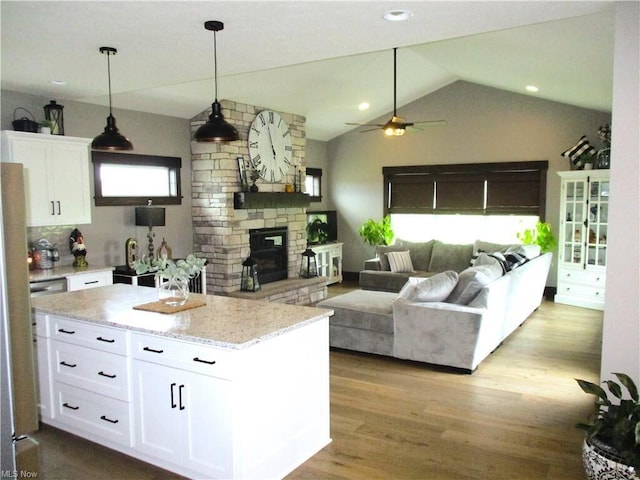 kitchen featuring lofted ceiling, ceiling fan, light hardwood / wood-style floors, light stone counters, and white cabinetry