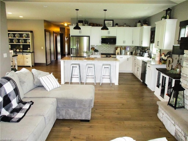 kitchen with white cabinetry, stainless steel appliances, decorative light fixtures, a breakfast bar area, and a kitchen island