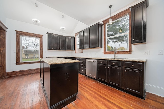 kitchen featuring lofted ceiling, sink, stainless steel dishwasher, decorative light fixtures, and a kitchen island