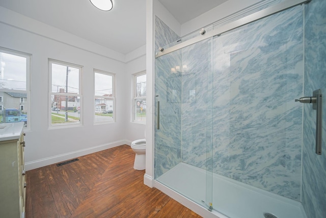 bathroom with hardwood / wood-style floors, vanity, a shower with shower door, and toilet