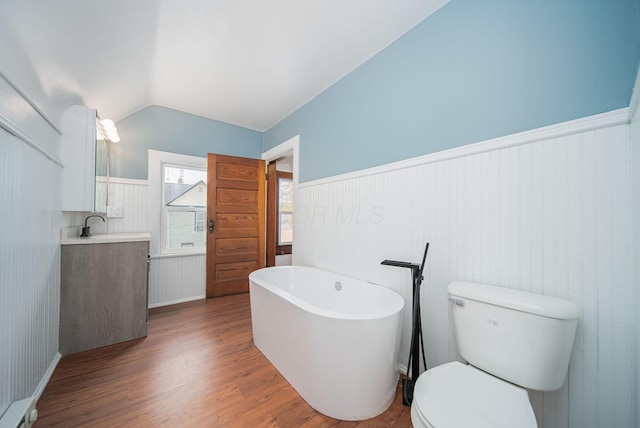 bathroom with a bathing tub, lofted ceiling, toilet, vanity, and hardwood / wood-style flooring