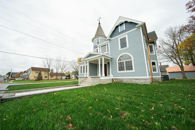 victorian home with central air condition unit and a front lawn