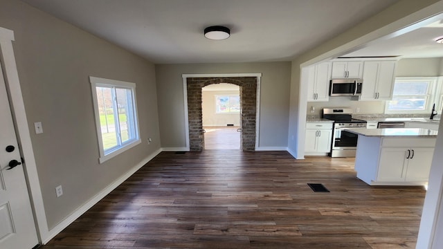 kitchen featuring a wealth of natural light, white cabinets, dark hardwood / wood-style floors, and appliances with stainless steel finishes