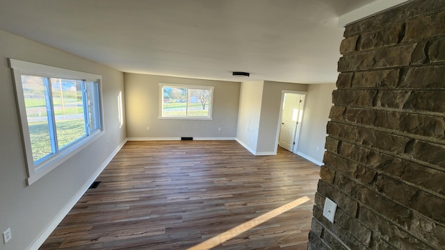 unfurnished living room with a healthy amount of sunlight and dark wood-type flooring