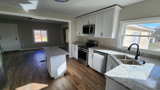 kitchen featuring appliances with stainless steel finishes, white cabinetry, dark wood-type flooring, and sink