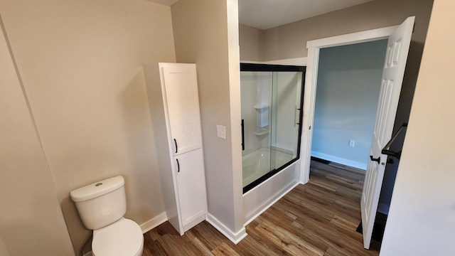 bathroom featuring toilet, wood-type flooring, and enclosed tub / shower combo