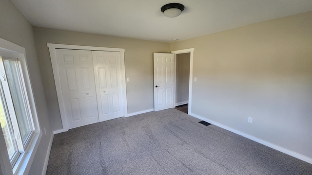 unfurnished bedroom with dark colored carpet and a closet