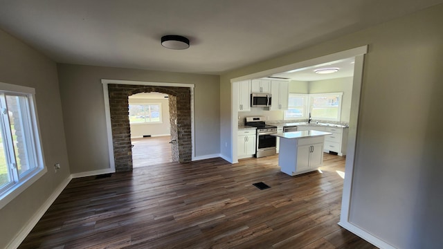 kitchen featuring white cabinets, dark hardwood / wood-style floors, a kitchen island, and stainless steel appliances