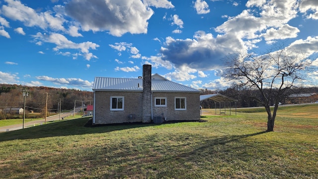 rear view of property featuring a lawn and a carport