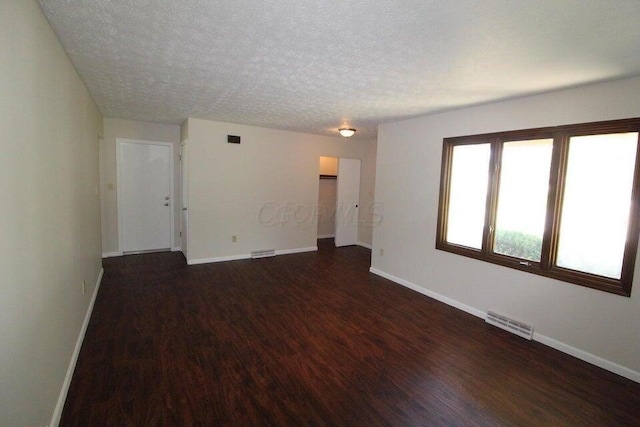 spare room with dark wood-type flooring and a textured ceiling