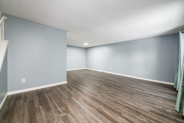 spare room featuring dark wood-style floors, a textured ceiling, and baseboards