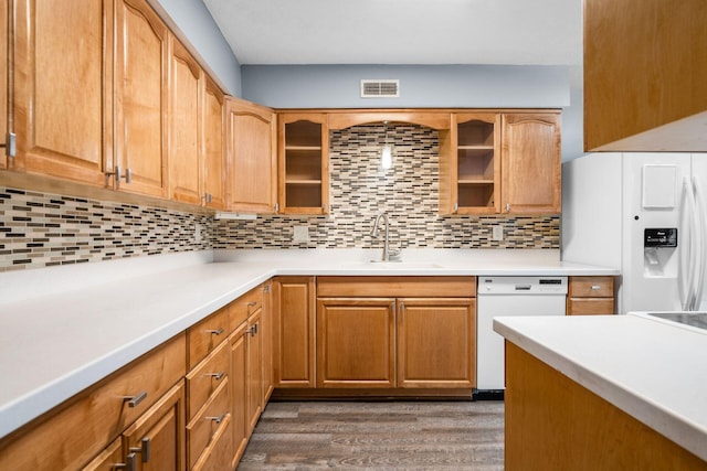 kitchen featuring white appliances, glass insert cabinets, light countertops, and a sink