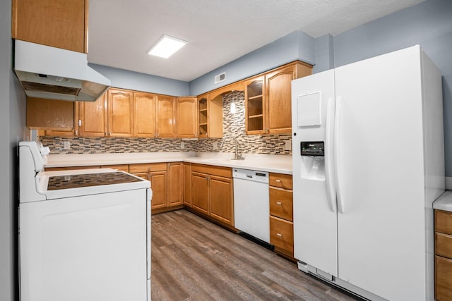 kitchen featuring light countertops, glass insert cabinets, a sink, white appliances, and under cabinet range hood