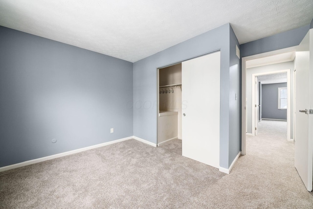 unfurnished bedroom with a textured ceiling, baseboards, a closet, and light colored carpet