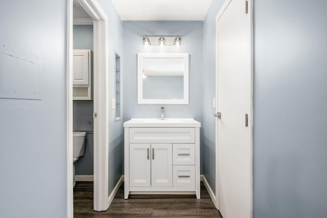 bathroom with baseboards, vanity, toilet, and wood finished floors