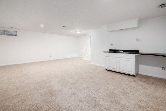 interior space with a textured ceiling, light colored carpet, baseboards, stairs, and indoor wet bar