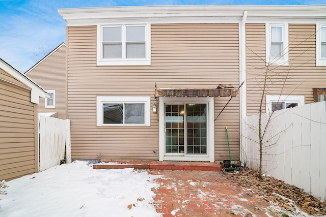 snow covered house with a fenced backyard