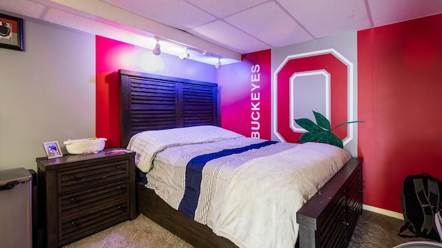 bedroom featuring carpet, track lighting, and a drop ceiling