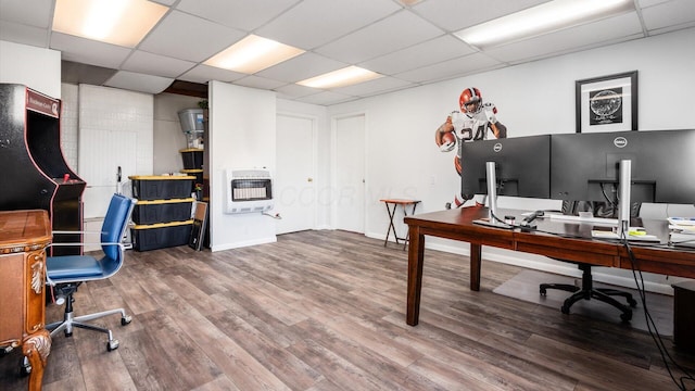 office area with heating unit, a paneled ceiling, and hardwood / wood-style floors