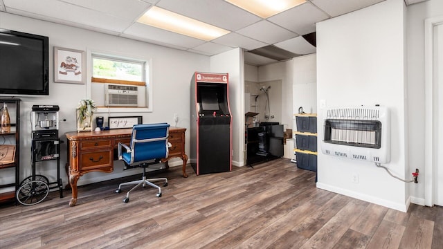 home office featuring a drop ceiling, heating unit, and hardwood / wood-style flooring