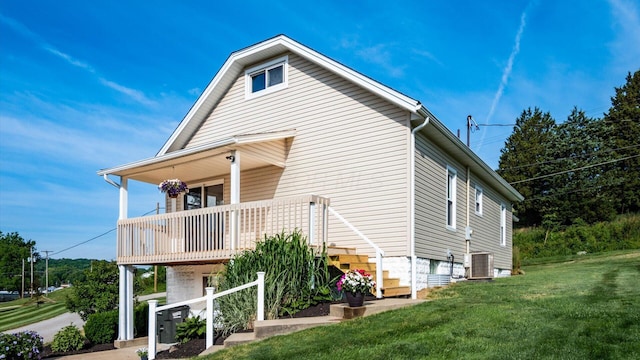 view of property exterior with covered porch, central AC unit, and a lawn