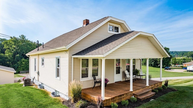 rear view of house with a lawn, central AC, and a porch