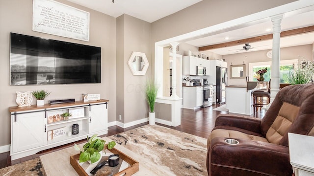 living room with decorative columns, ceiling fan, dark wood-type flooring, sink, and beam ceiling