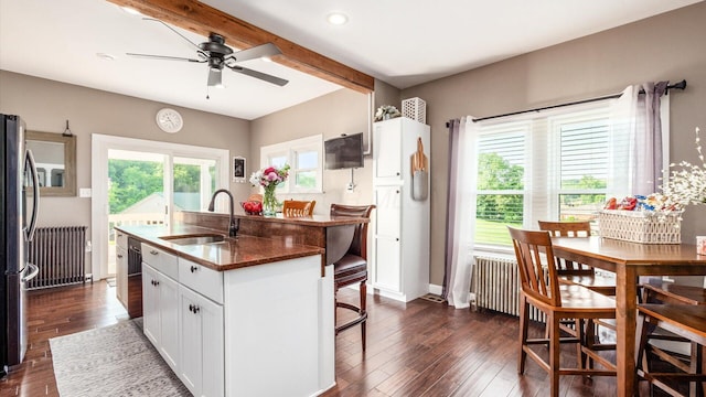 kitchen with a kitchen bar, dark wood-type flooring, sink, white cabinets, and an island with sink