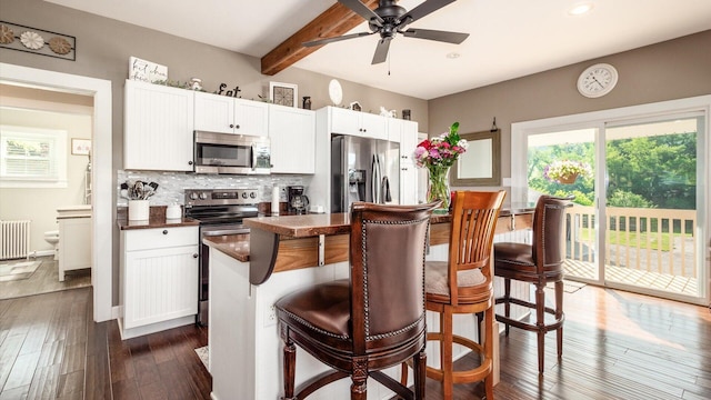 kitchen with a kitchen island, dark hardwood / wood-style flooring, a breakfast bar area, and appliances with stainless steel finishes