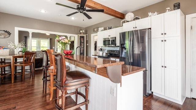 kitchen featuring white cabinets, dark hardwood / wood-style floors, dark stone countertops, a kitchen island, and stainless steel appliances