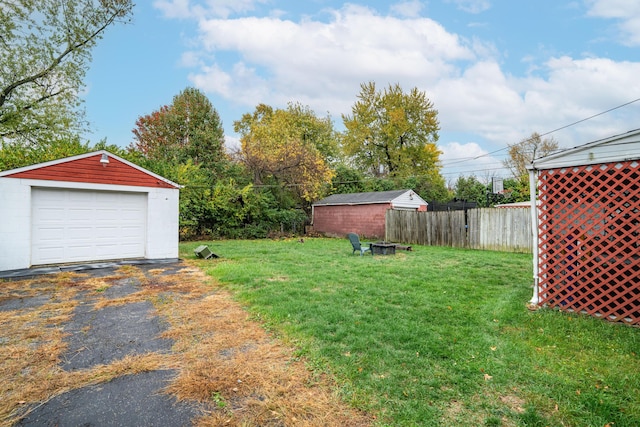 view of yard featuring a garage, an outdoor fire pit, and an outbuilding