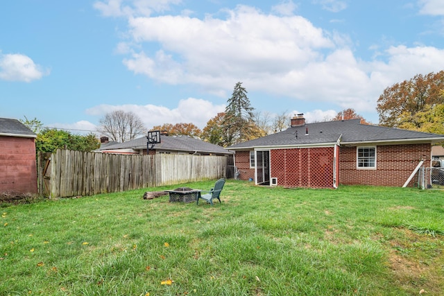 rear view of property featuring an outdoor fire pit and a lawn