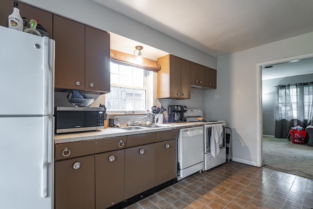 kitchen with sink, white appliances, dark carpet, and dark brown cabinetry