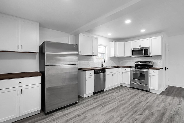 kitchen with tasteful backsplash, stainless steel appliances, sink, light hardwood / wood-style floors, and white cabinetry