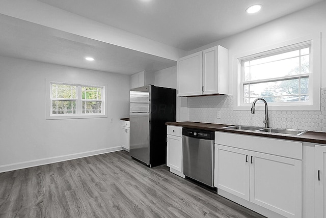 kitchen with white cabinetry, sink, light hardwood / wood-style flooring, backsplash, and appliances with stainless steel finishes